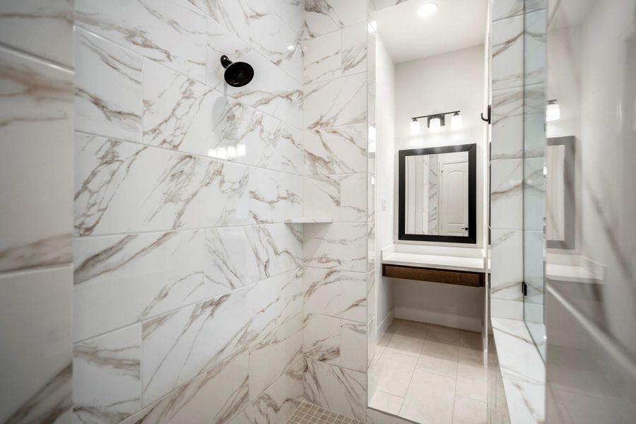 This large modern shower has elegant tile finishes to the ceiling. The bright and clean design creates a luxurious feel, complemented by black fixtures.