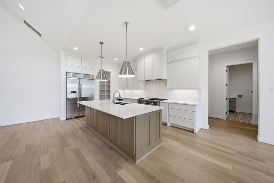 Chef-inspired kitchen showcasing an oversized quartz island, custom cabinetry, premium appliances, and timeless designer finishes.