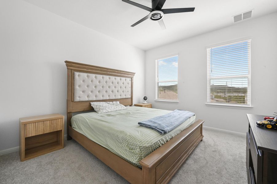 Plentiful natural light streams through multiple windows highlighting the comfortable carpeted floors.