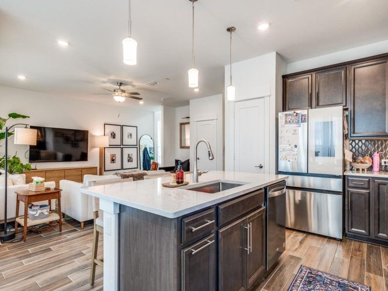 Kitchen featuring stainless steel appliances, light wood-style floors, open floor plan, dark brown cabinets, and backsplash