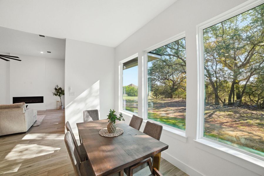 Dining space featuring light wood-type flooring, ceiling fan, and a fireplace Dining space featuring light wood-type flooring, ceiling fan, and a fireplace