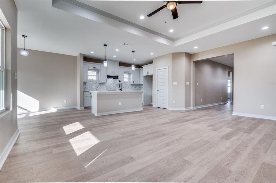 Unfurnished living room featuring visible vents, baseboards, light wood-style flooring, recessed lighting, and a sink