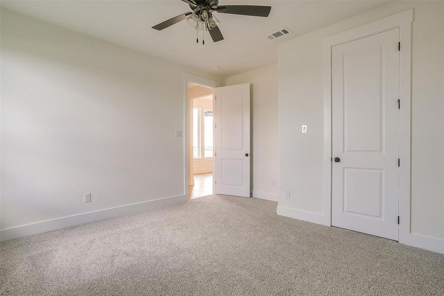 Unfurnished bedroom with ceiling fan and light carpet