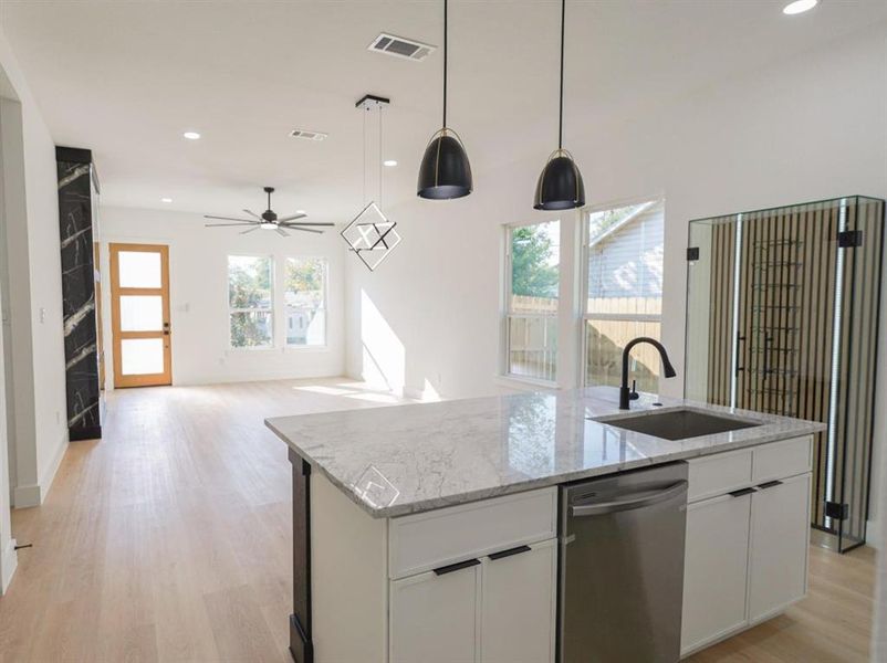 Kitchen featuring recessed lighting, stainless steel dishwasher, white cabinetry, light wood-style floors, and decorative light fixtures Kitchen featuring recessed lighting, stainless steel dishwasher, white cabinetry, light wood-style floors, and decorative light fixtures