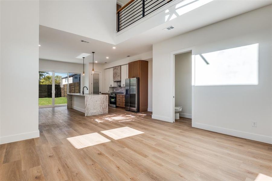 Unfurnished living room featuring light wood finished floors, recessed lighting, and a high ceiling