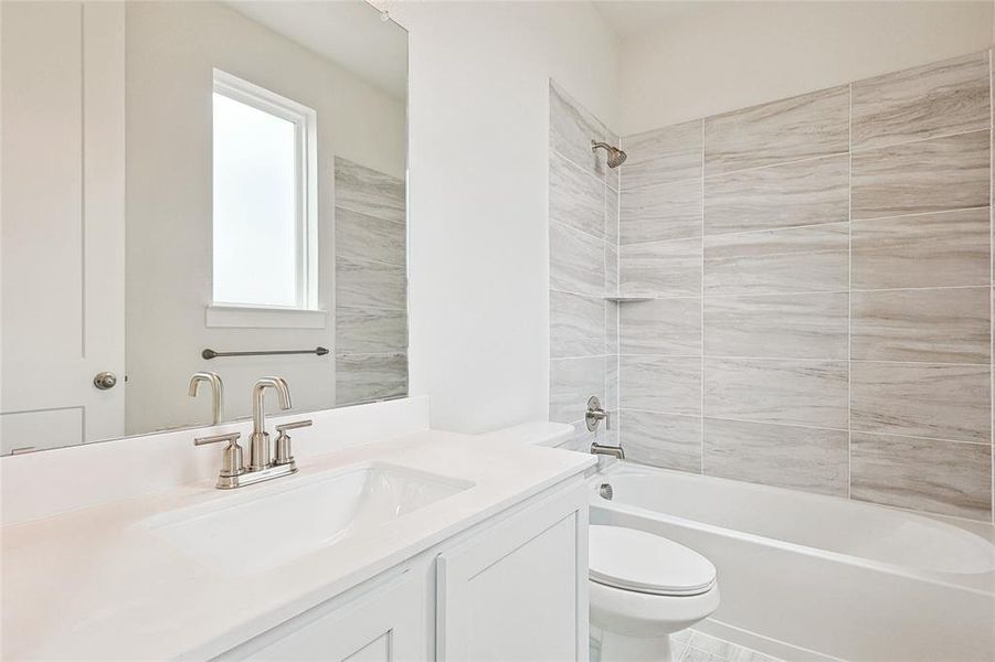 Full bathroom with tile patterned floors, toilet, vanity, and tiled shower / bath