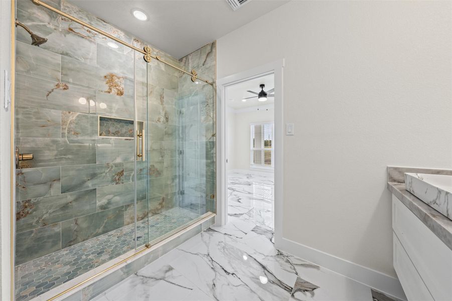 Gleaming marble-patterned tile floors complement a spacious walk-in shower framed by glass sliding doors.