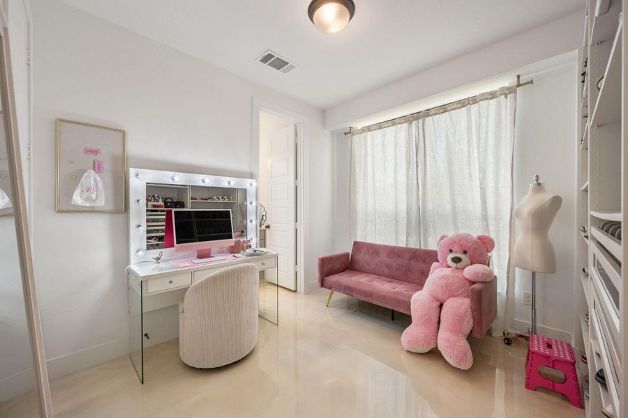 A well-lit bedroom offers a vanity with integrated lighting and ample shelving for organized storage. A well-lit bedroom offers a vanity with integrated lighting and ample shelving for organized storage.