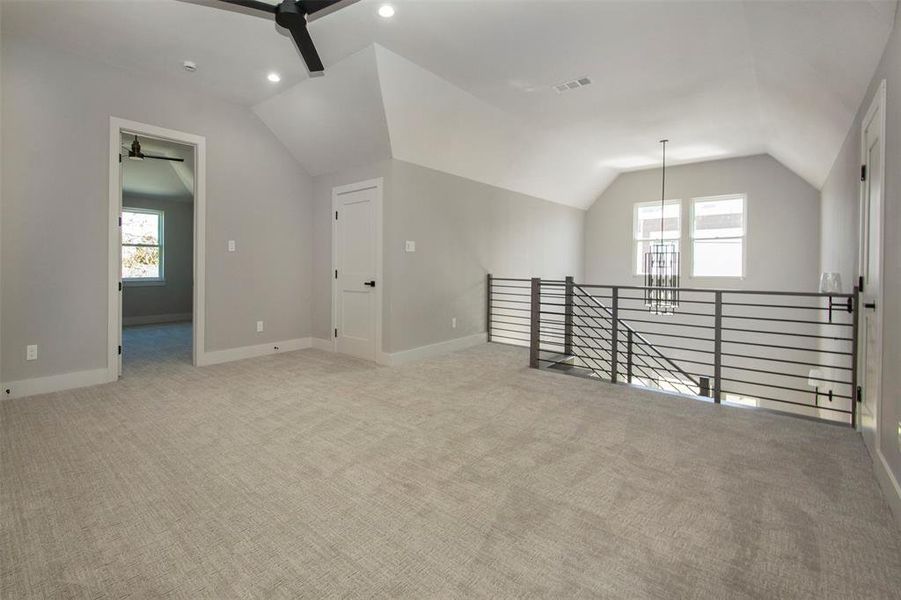 Additional living space featuring ceiling fan, light carpet, and lofted ceiling