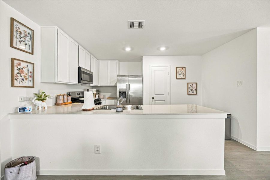 Modern kitchen with sleek white cabinetry, stainless steel appliances, and a spacious countertop, perfect for meal preparation and entertaining.