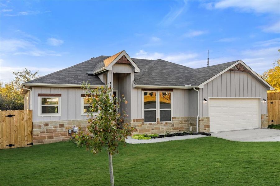 Single story home with stone siding, a shingled roof, and a garage