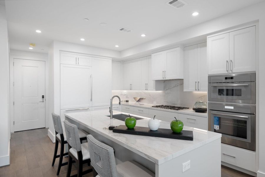 Featuring sleek white cabinetry, elegant quartz countertops, and a marble backsplash. Featuring sleek white cabinetry, elegant quartz countertops, and a marble backsplash.