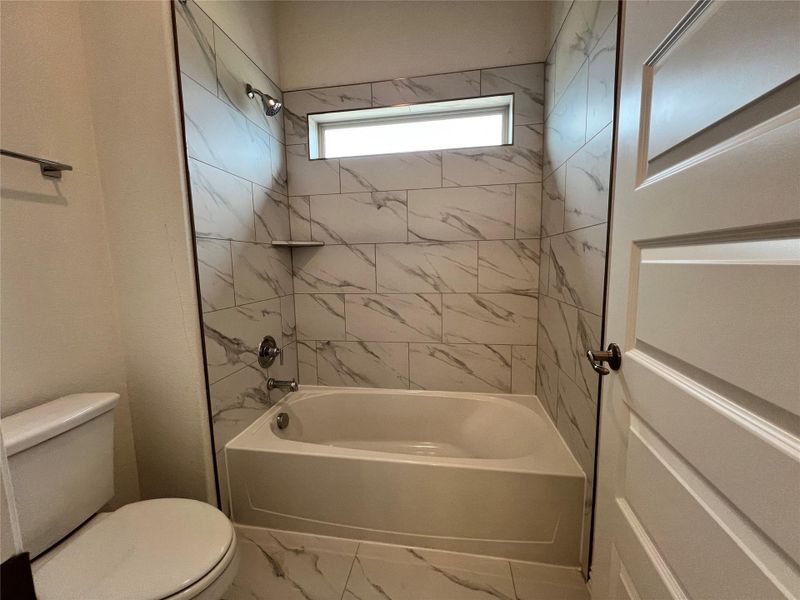 Bathroom with bathtub / shower combination and marble look tile flooring Bathroom with bathtub / shower combination and marble look tile flooring