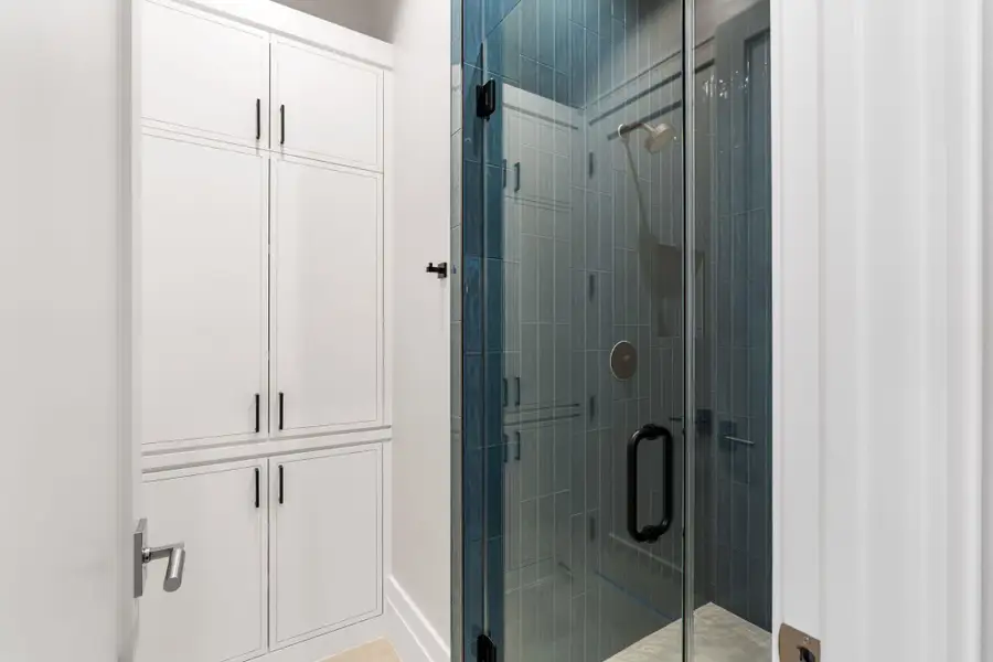 Guest bath with glass frame shower, abundant cabinetry and chic tile design.