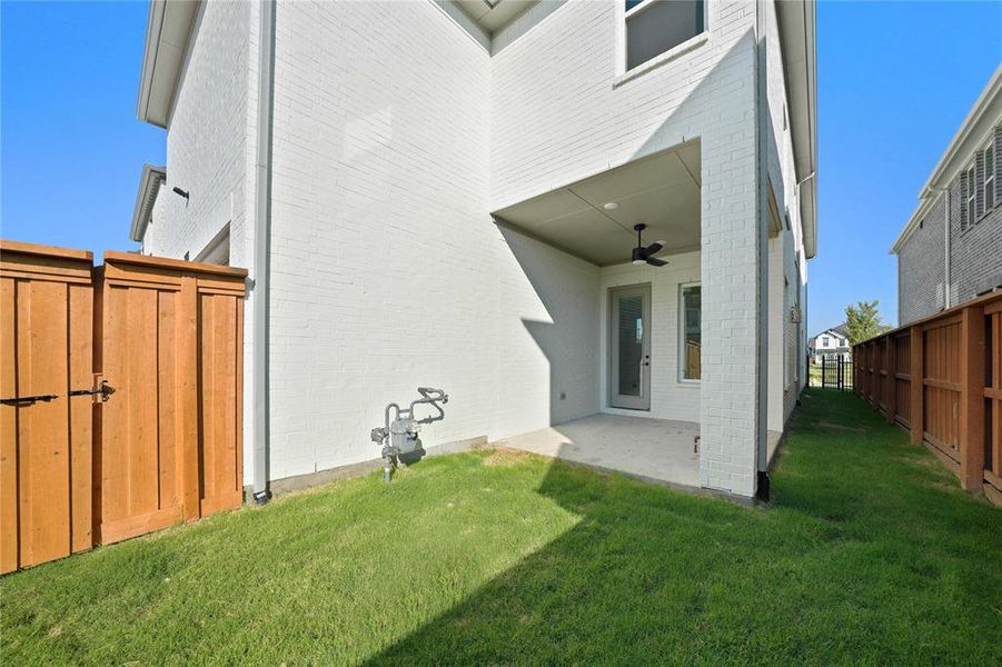 Rear view of property featuring brick siding, a patio area, and ceiling fan Rear view of property featuring brick siding, a patio area, and ceiling fan