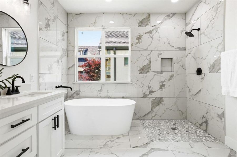 Contemporary bathroom featuring a freestanding tub, a walk-in shower with mosaic tile flooring, a single vanity with a quartz countertop, and large format marble-look wall and floor tiling Contemporary bathroom featuring a freestanding tub, a walk-in shower with mosaic tile flooring, a single vanity with a quartz countertop, and large format marble-look wall and floor tiling