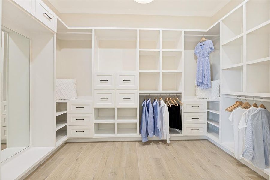 Custom white built-in closet system featuring multiple hanging rods, varied shelving, and drawer storage
