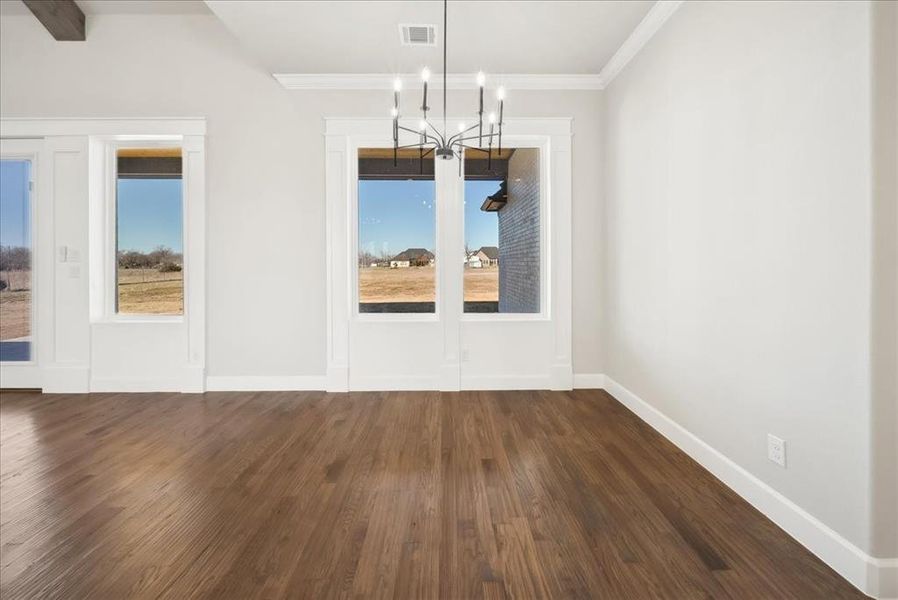 Unfurnished dining area with dark hardwood / wood-style flooring, ornamental molding, and a chandelier