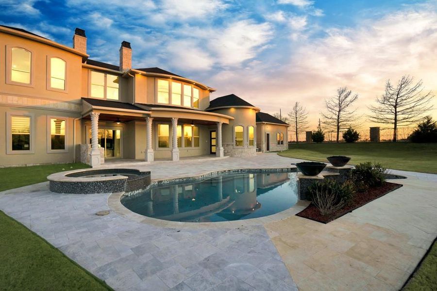 Pool at dusk featuring an in ground hot tub, a yard, and a patio