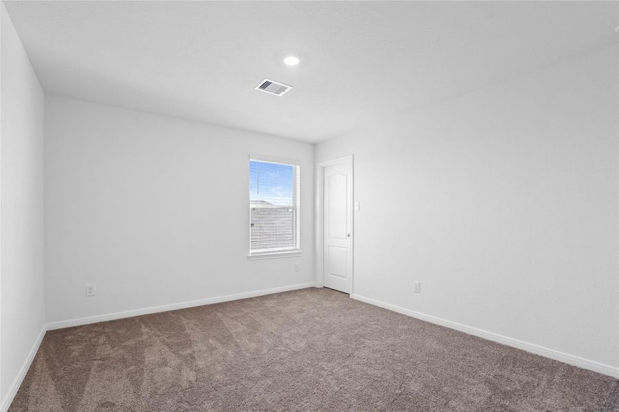 This secondary bedroom offers comfort and style with plush carpeting, neutral paint tones, recessed lighting, a large window with blinds, and a walk-in closet. This secondary bedroom offers comfort and style with plush carpeting, neutral paint tones, recessed lighting, a large window with blinds, and a walk-in closet.