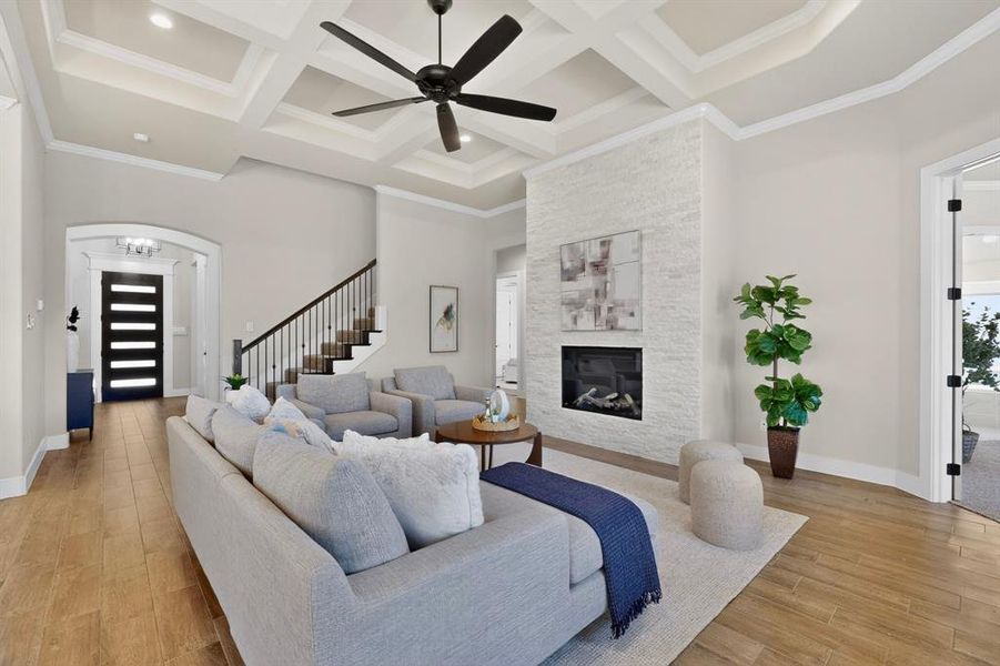 Living area featuring wood-finish flooring, a contemporary fireplace with a light-toned stone surround, and a ceiling fan