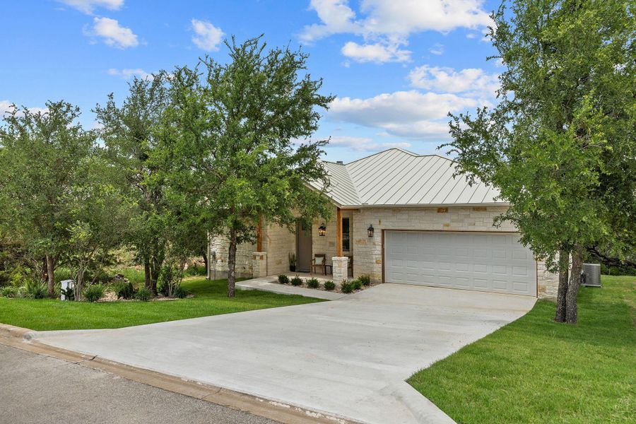 View of front of property featuring stone siding, concrete driveway, and a front lawn View of front of property featuring stone siding, concrete driveway, and a front lawn