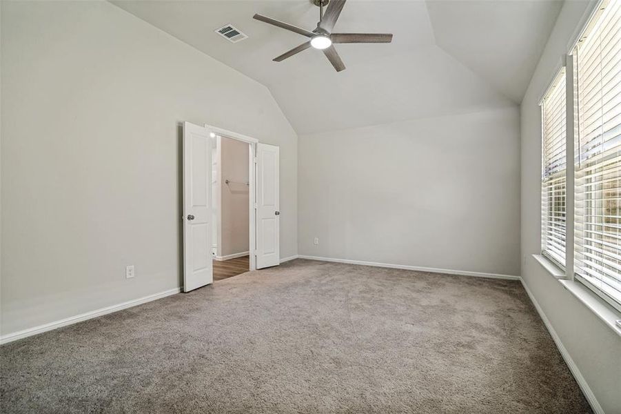 Spacious room featuring vaulted ceilings, a ceiling fan with integrated lighting, and carpet flooring Spacious room featuring vaulted ceilings, a ceiling fan with integrated lighting, and carpet flooring
