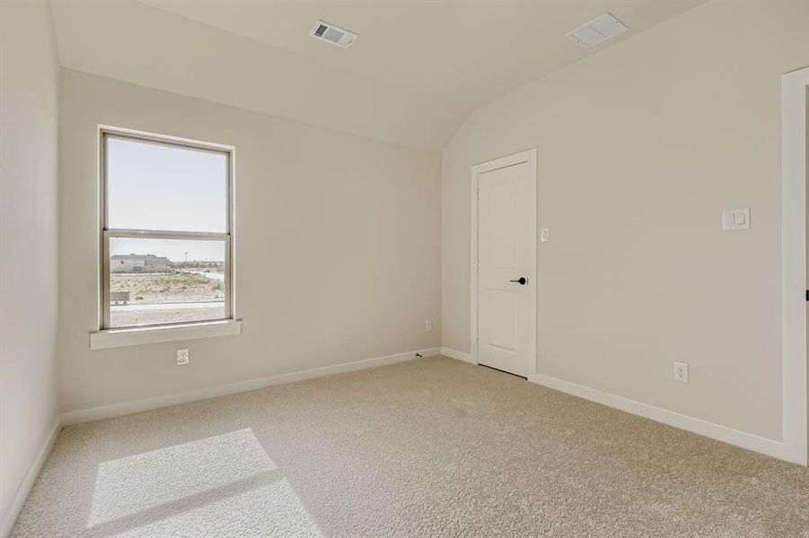 Empty room featuring vaulted ceiling and light carpet