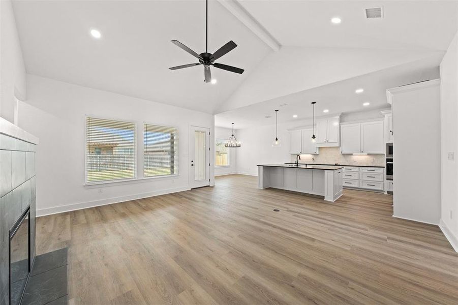 Unfurnished living room with suspended lighting, a ceiling fan, a fireplace, and light wood-style floors