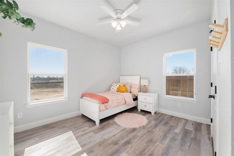 Bedroom featuring multiple windows, ceiling fan, and light hardwood / wood-style floors