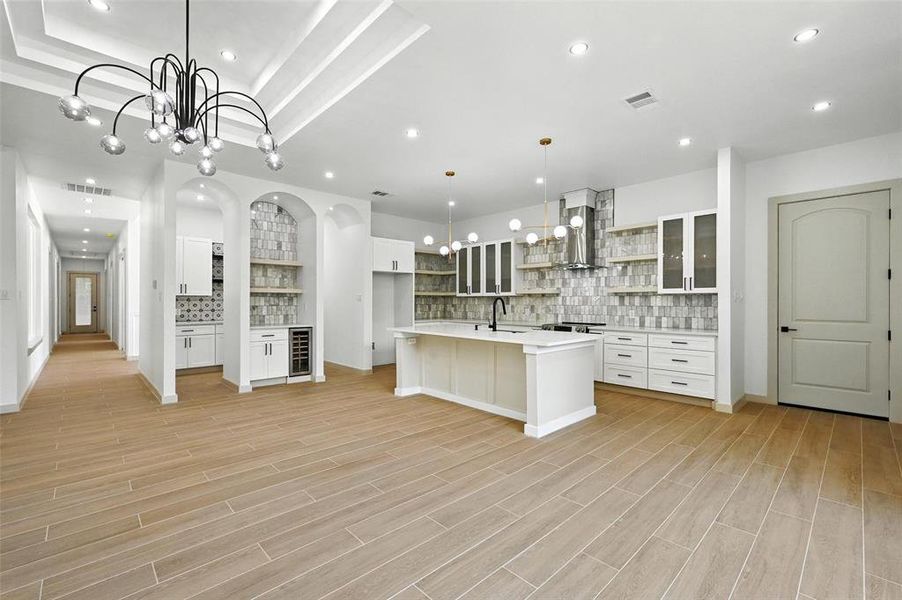 Kitchen featuring tasteful backsplash, open shelves, white cabinets, light countertops, and recessed lighting Kitchen featuring tasteful backsplash, open shelves, white cabinets, light countertops, and recessed lighting