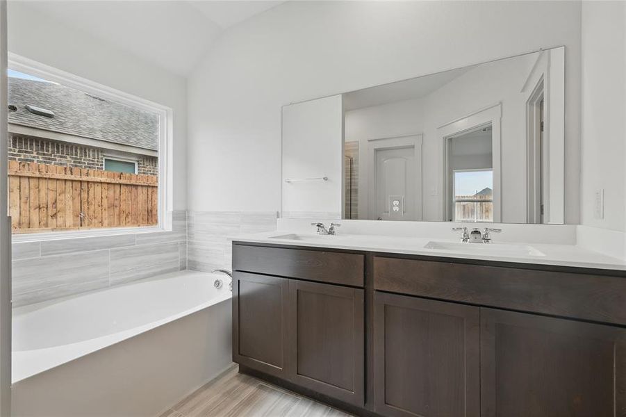 Bathroom featuring double vanity, a garden tub, healthy amount of natural light, and vaulted ceiling Bathroom featuring double vanity, a garden tub, healthy amount of natural light, and vaulted ceiling