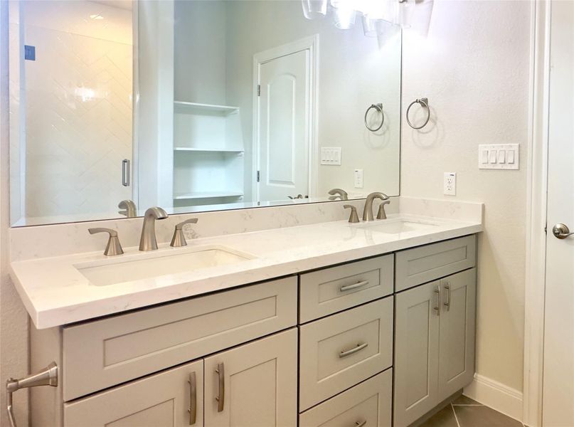 Full bath featuring double vanity, tile patterned flooring, and a shower stall Full bath featuring double vanity, tile patterned flooring, and a shower stall