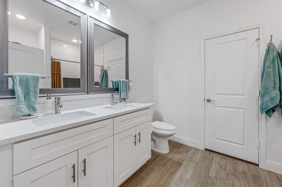 Full bathroom with light wood-type flooring, double vanity, and a shower with curtain