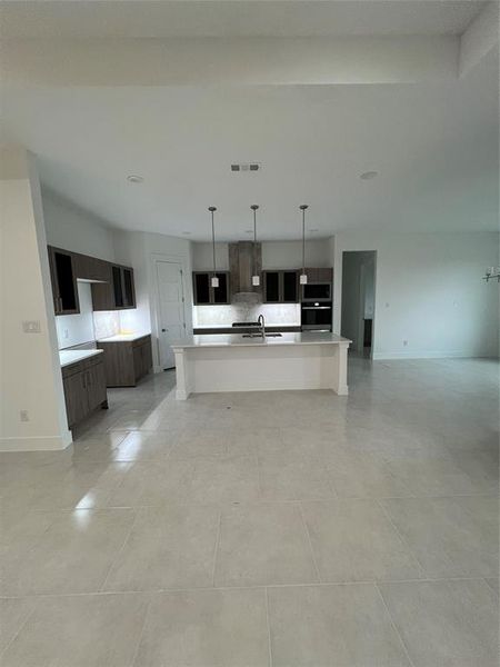 Kitchen featuring a center island with sink, pendant lighting, dark brown cabinetry, and sink