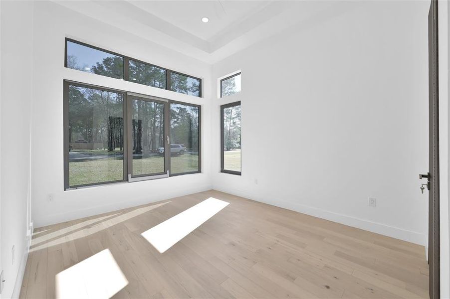 Bright front-facing bedroom with large windows and natural light.