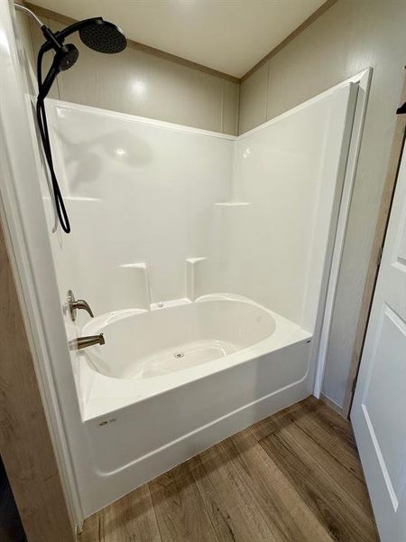 Bathroom featuring wood finished floors and washtub / shower combination Bathroom featuring wood finished floors and washtub / shower combination