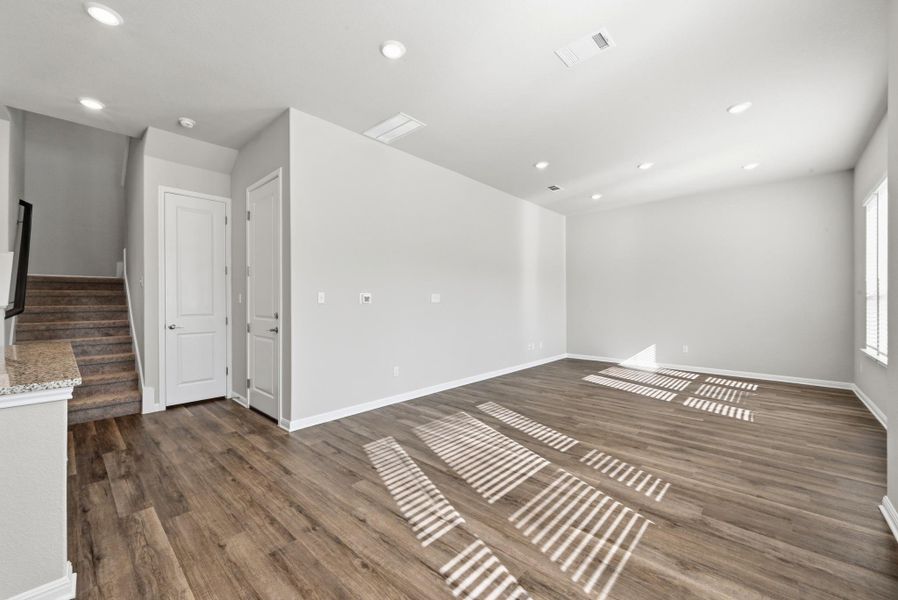 Spacious room featuring wood-finish flooring, recessed lighting, and light gray wall tones Spacious room featuring wood-finish flooring, recessed lighting, and light gray wall tones