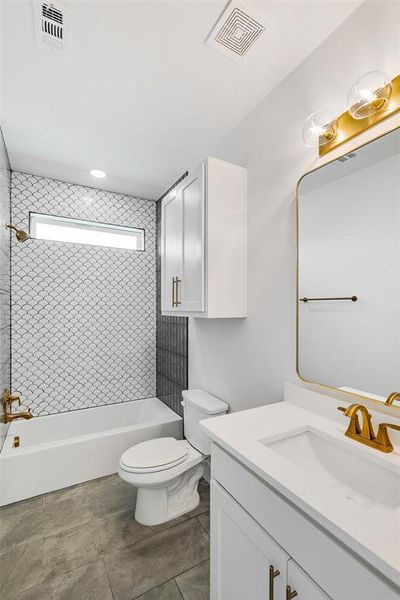 Full bathroom featuring vanity, toilet, tile patterned floors, and tiled shower / bath