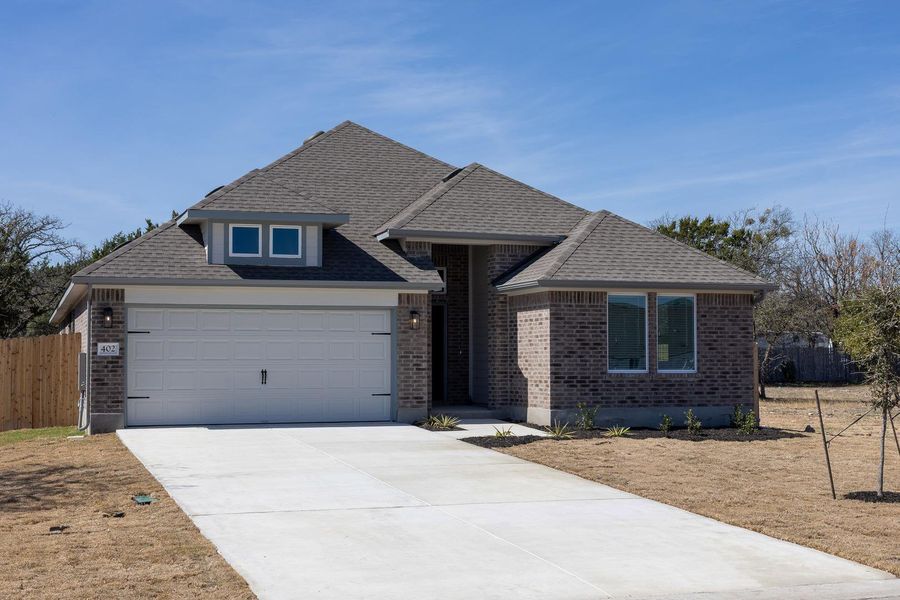 View of front of home featuring brick siding, roof with shingles, concrete driveway, and an attached garage