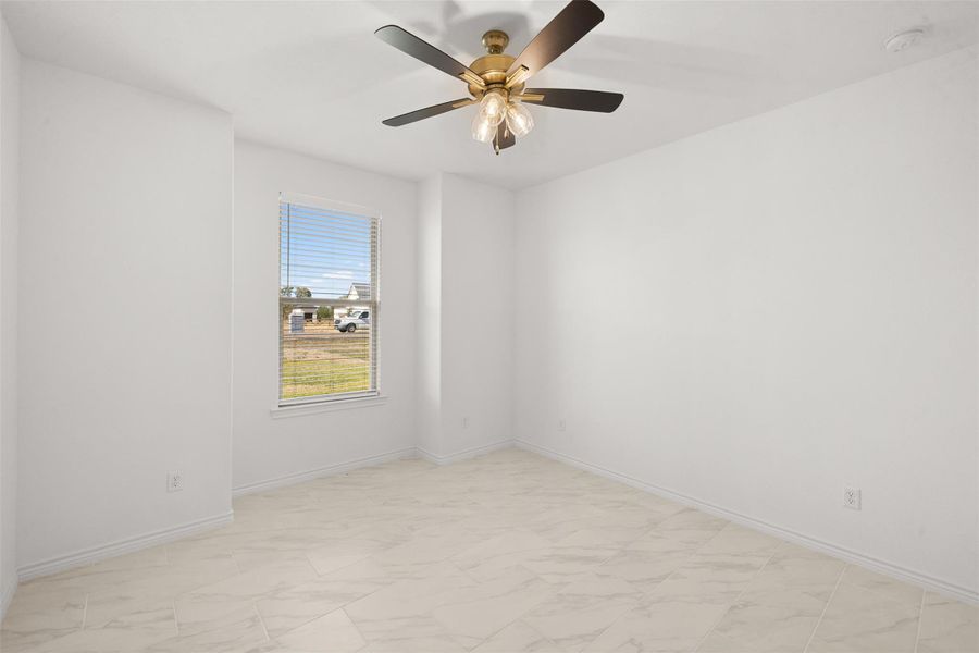 Spare room with light marble finish flooring and a ceiling fan