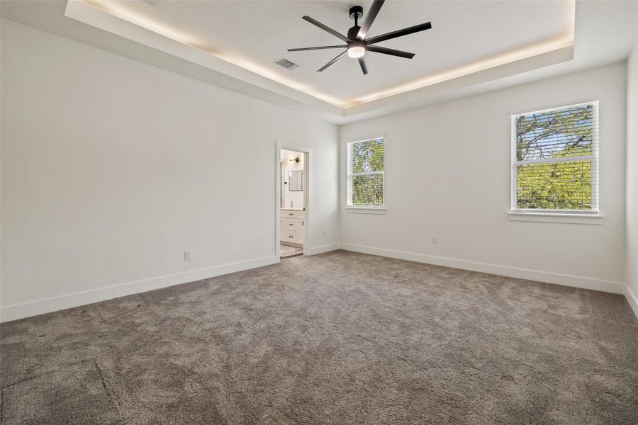 Carpeted spare room with a tray ceiling and a ceiling fan Carpeted spare room with a tray ceiling and a ceiling fan