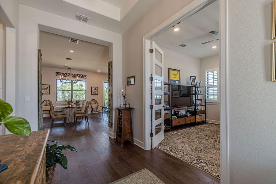 Hall with dark wood finished floors, plenty of natural light, a chandelier, and recessed lighting