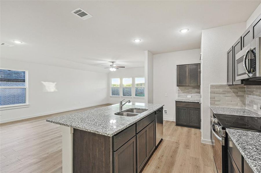 Kitchen with light hardwood / wood-style flooring, stainless steel appliances, backsplash, and sink