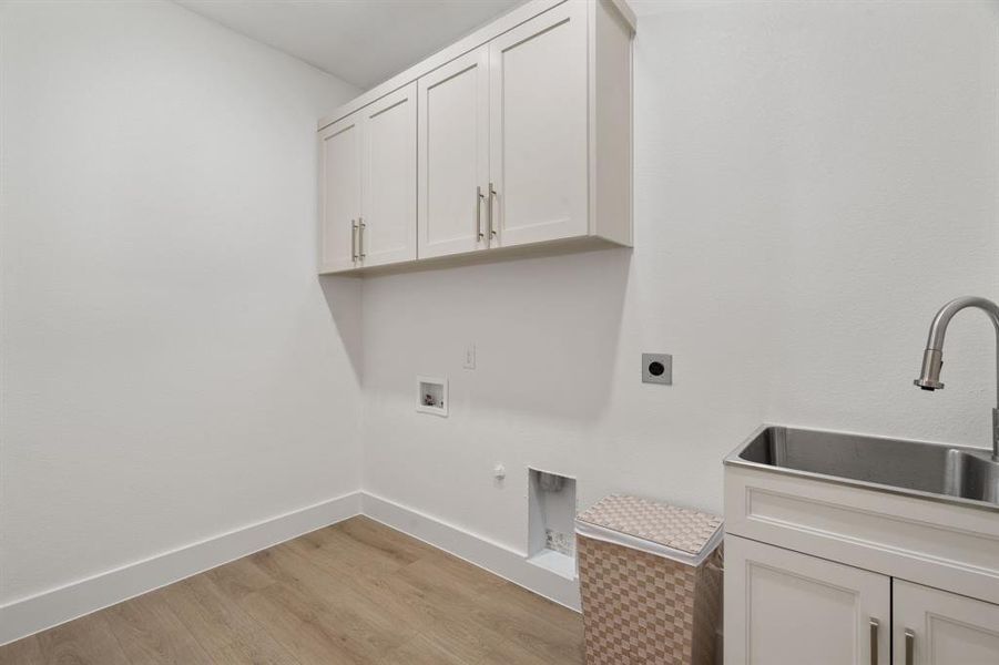Laundry room with cabinet space, light wood-type flooring, hookup for a gas dryer, electric dryer hookup, and hookup for a washing machine Laundry room with cabinet space, light wood-type flooring, hookup for a gas dryer, electric dryer hookup, and hookup for a washing machine