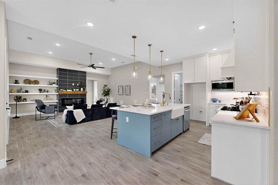 Kitchen featuring white cabinets, a breakfast bar area, open floor plan, light wood-style floors, and pendant lighting