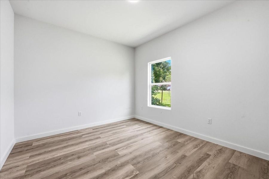 Another view of a bright secondary bedroom with clean lines and uniform modern flooring. Another view of a bright secondary bedroom with clean lines and uniform modern flooring.