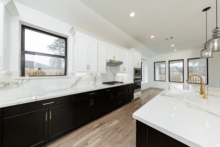 This modern culinary space features a striking tuxedo-style design with crisp white upper and sleek black lower cabinets, all accented by elegant brushed gold faucet.