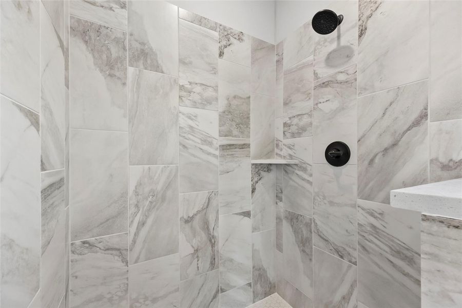 This photo showcases a modern shower with elegant marble-style tiling, a sleek black showerhead, and a built-in shelf for convenience. This photo showcases a modern shower with elegant marble-style tiling, a sleek black showerhead, and a built-in shelf for convenience.