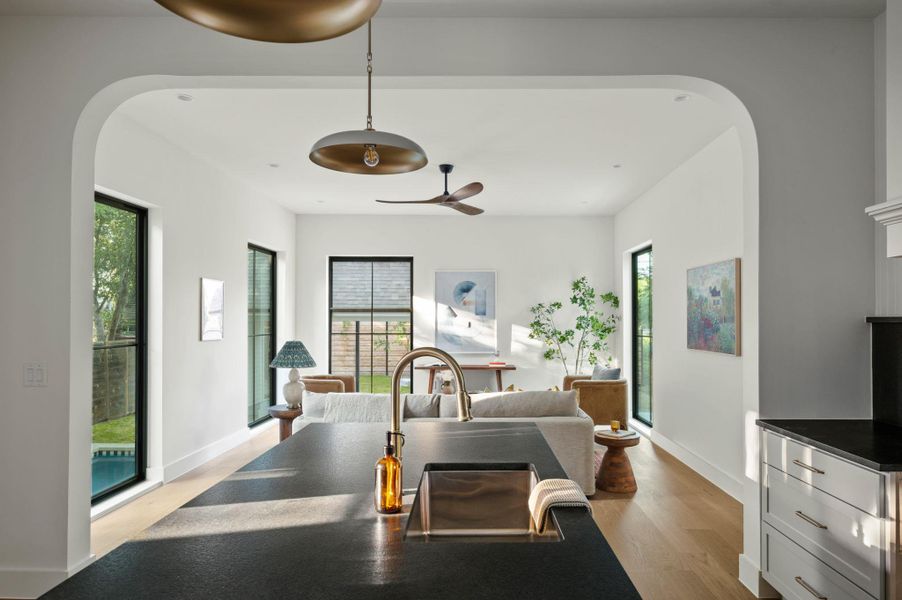 An open concept living area features ample natural light, pristine hardwood floors, and a modern kitchen island with a sleek sink.